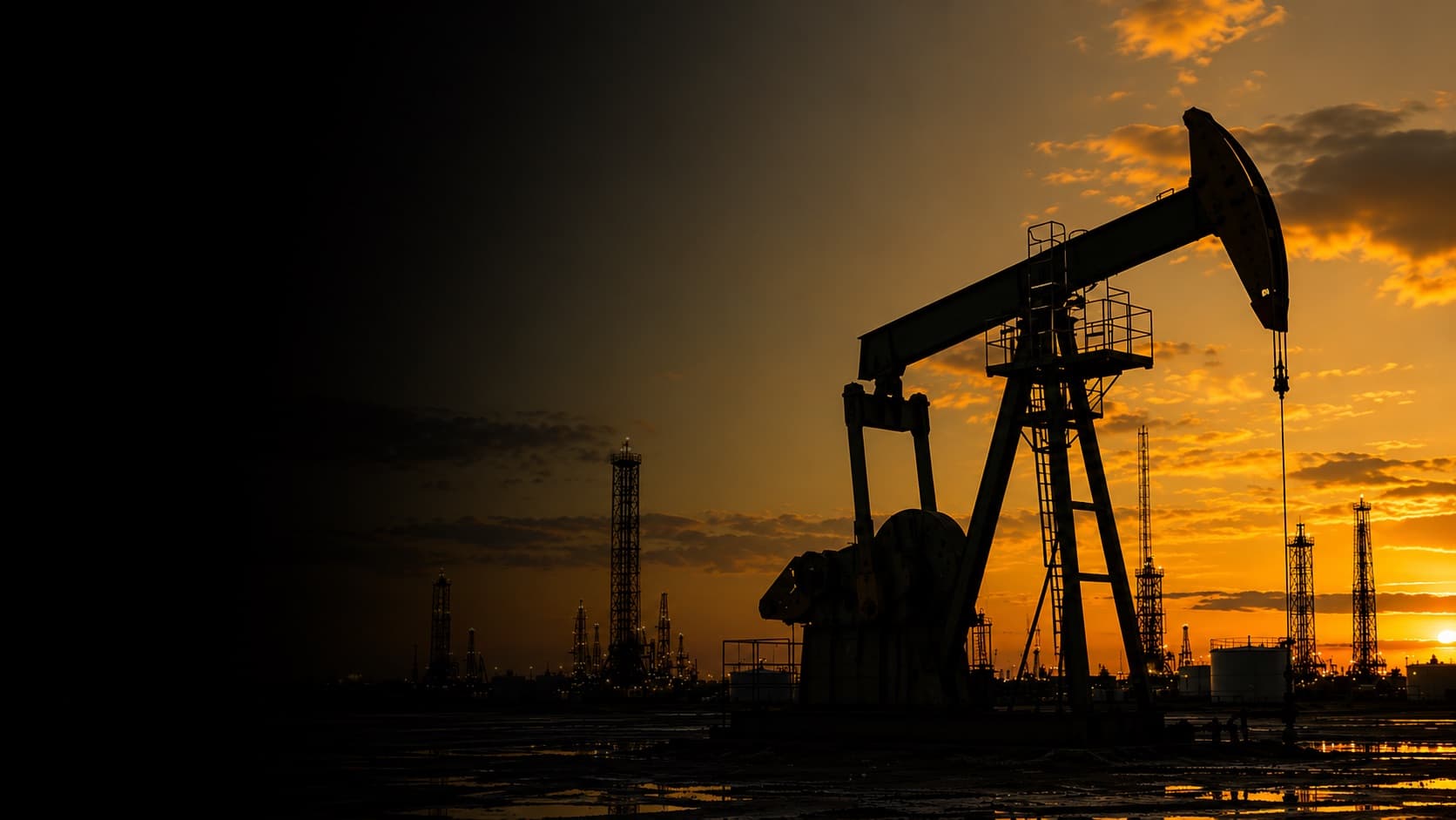 Pumpjacks and drilling rigs silhouetted at sunset